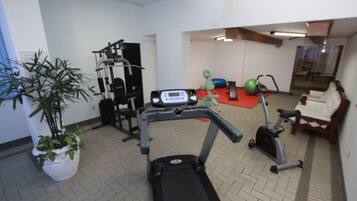 Un gimnasio con cinta de correr, máquinas de pesas y bicicleta estática.