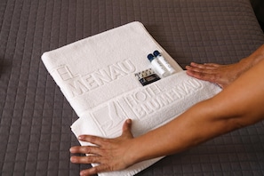 A white towel with embossed text on a bed. - Hotel Blumenau (Balneário Camboriú)