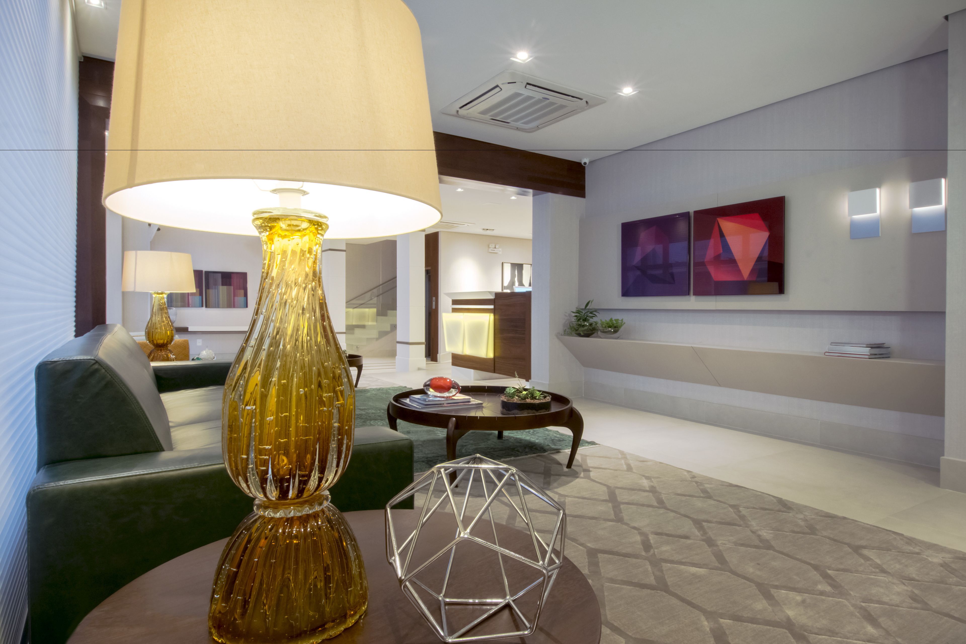 A modern living room with a large lamp, a geometric glass sculpture, and a sofa.