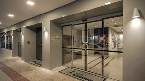 A modern hotel entrance with glass doors, a doormat, and a sign reading "Hotel Blumenau." - Hotel Blumenau (Balneário Camboriú)