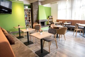 Ein stilvoller Lounge-Bereich mit Sitzgelegenheiten, Tischen, einem Kamin und einem Bücherregal.
