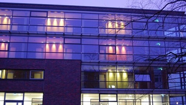 Un bâtiment moderne doté de nombreuses fenêtres et portes en verre, et offrant un éclairage combinant des sources naturelles et artificielles.