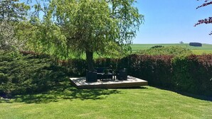 A patio area with a seating arrangement and a view of a green field.