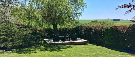 Un patio con un conjunto de asientos y vistas a un campo verde.