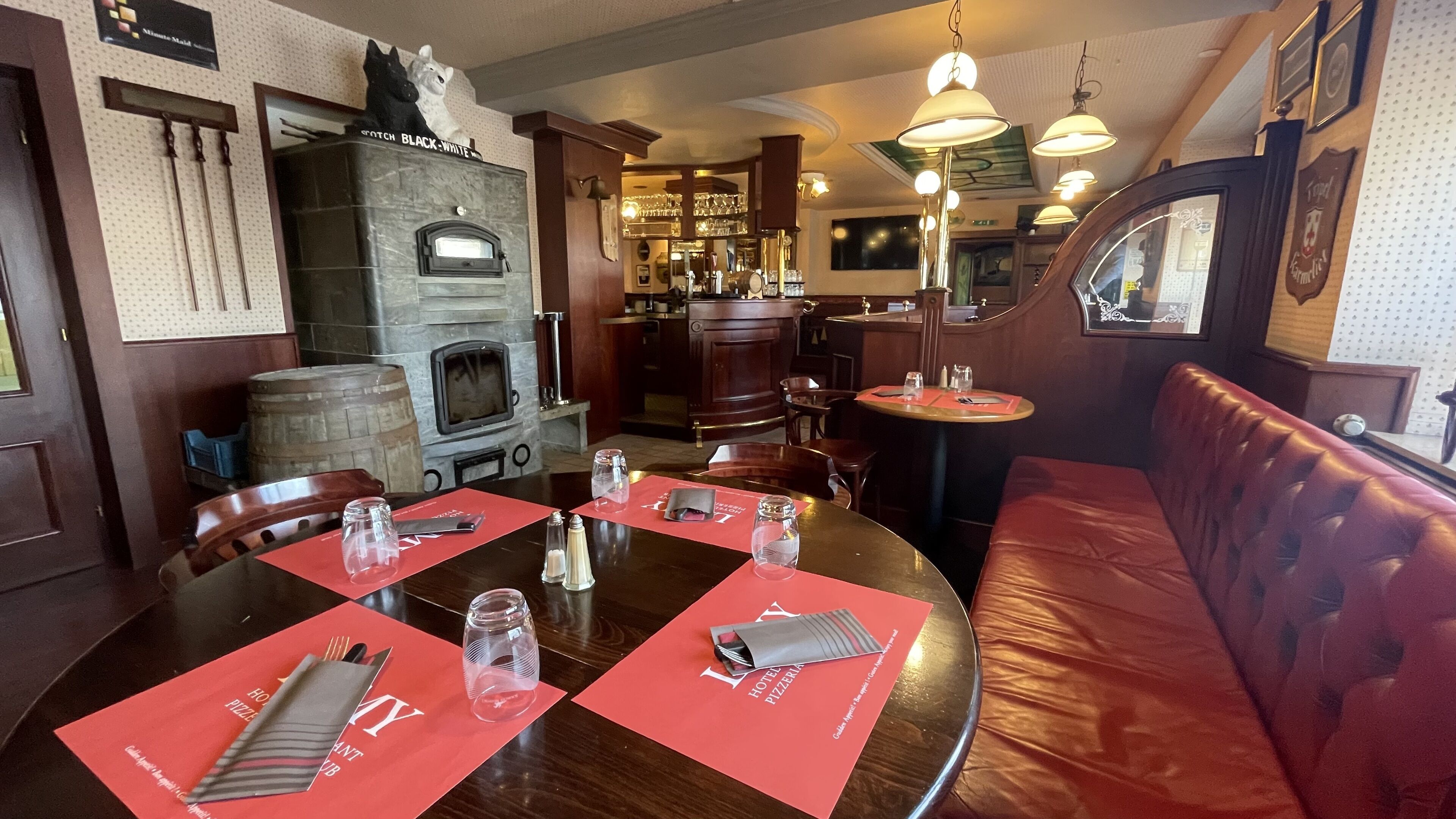 Un restaurante con chimenea de piedra, muebles de madera y manteles individuales rojos.