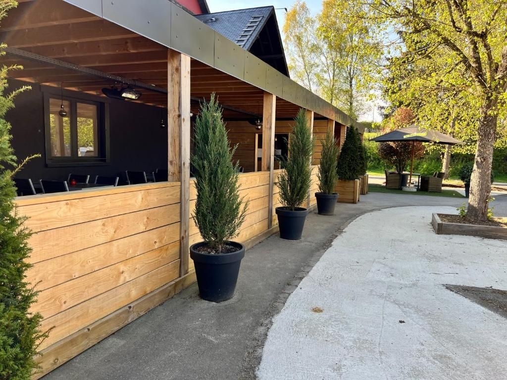 Un espace extérieur abrité, doté de murs en bois et agrémenté de plantes en pot.