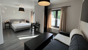 A modern hotel room with a bed, desk, and seating area.