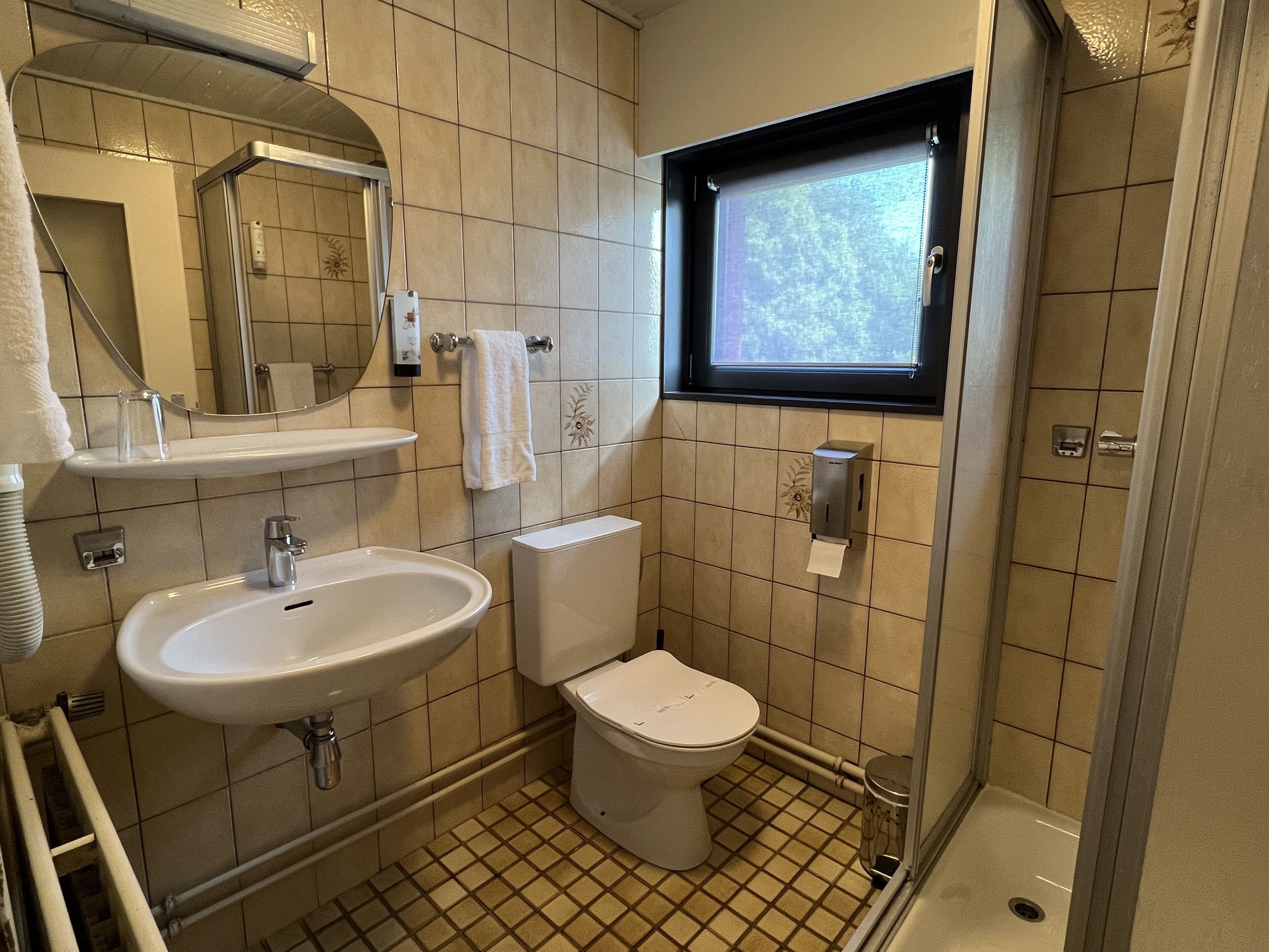 A bathroom with a sink, toilet, and a window.