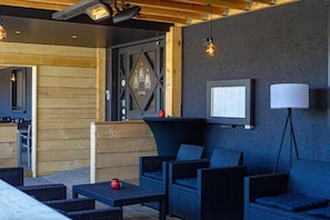 A modern outdoor seating area with wicker furniture, a wall-mounted TV, and a lamp. - Hôtel Restaurant Lamy (Troisvierges)