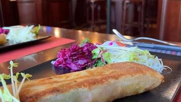 Ein Esstisch mit einem Teller Essen, darunter ein Brötchen und ein Salat.