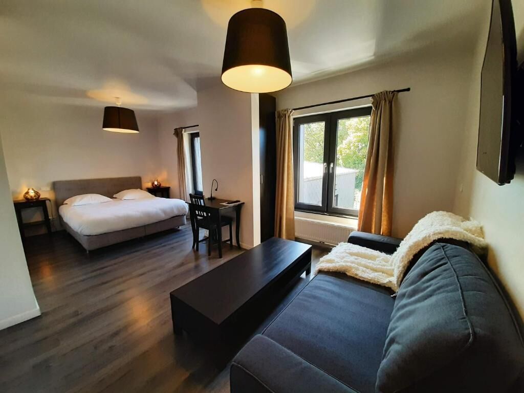Une chambre d’hôtel moderne équipée d’un lit, d’un canapé, d’un bureau et d’une grande fenêtre.