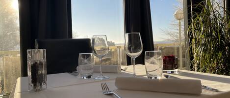 A table set for dining with wine glasses, a water glass, and a fork, overlooking a scenic view.