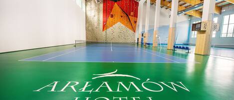 An indoor climbing wall at Aramov Hotel with a blue floor and a large climbing wall in the background.