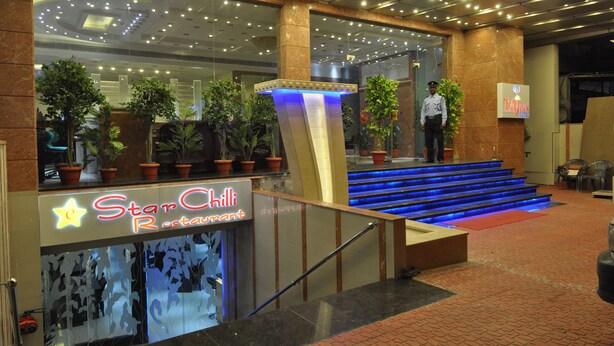 A Star Chilli restaurant with a modern entrance, potted plants, and a blue-lit staircase. - Hotel Taj Inn (Agra)