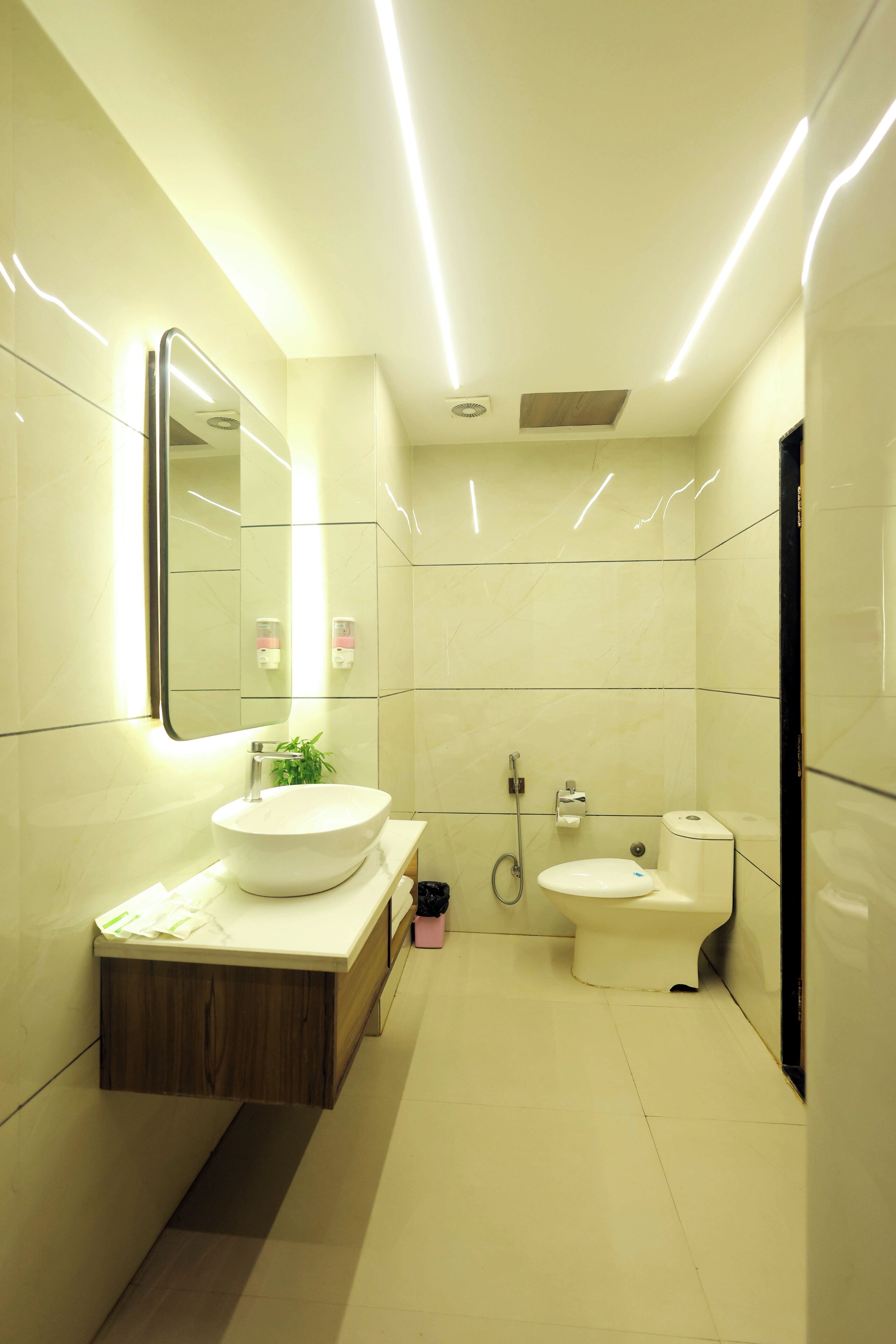 A modern bathroom with a white sink, mirror, and toilet.
