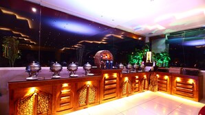 A modern bar area with a long counter, decorative lighting, and a large screen. - Hotel Taj Inn (Agra)