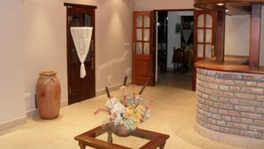 A spacious room with a wooden table, a large vase, and a brick accent wall.