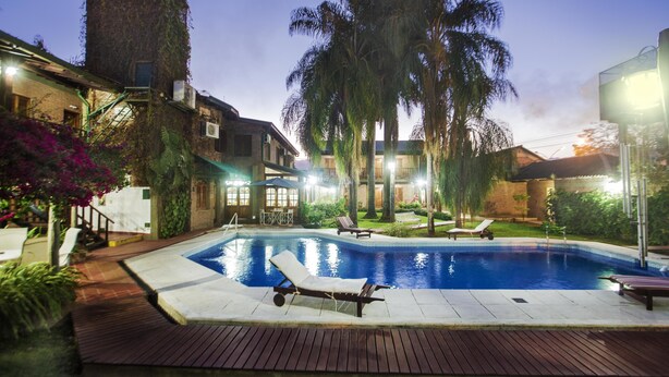 A swimming pool with lounge chairs, surrounded by palm trees and a wooden deck.