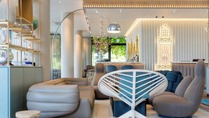 A modern living room with a sofa, a unique chair, and a bar area with a decorative wall. - Motel One Rostock (Rostock)