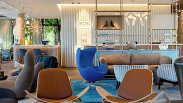 Een modern interieur met een bar, zitplaatsen met een blauwe stoel en een boekenkast met decoratieve objecten.