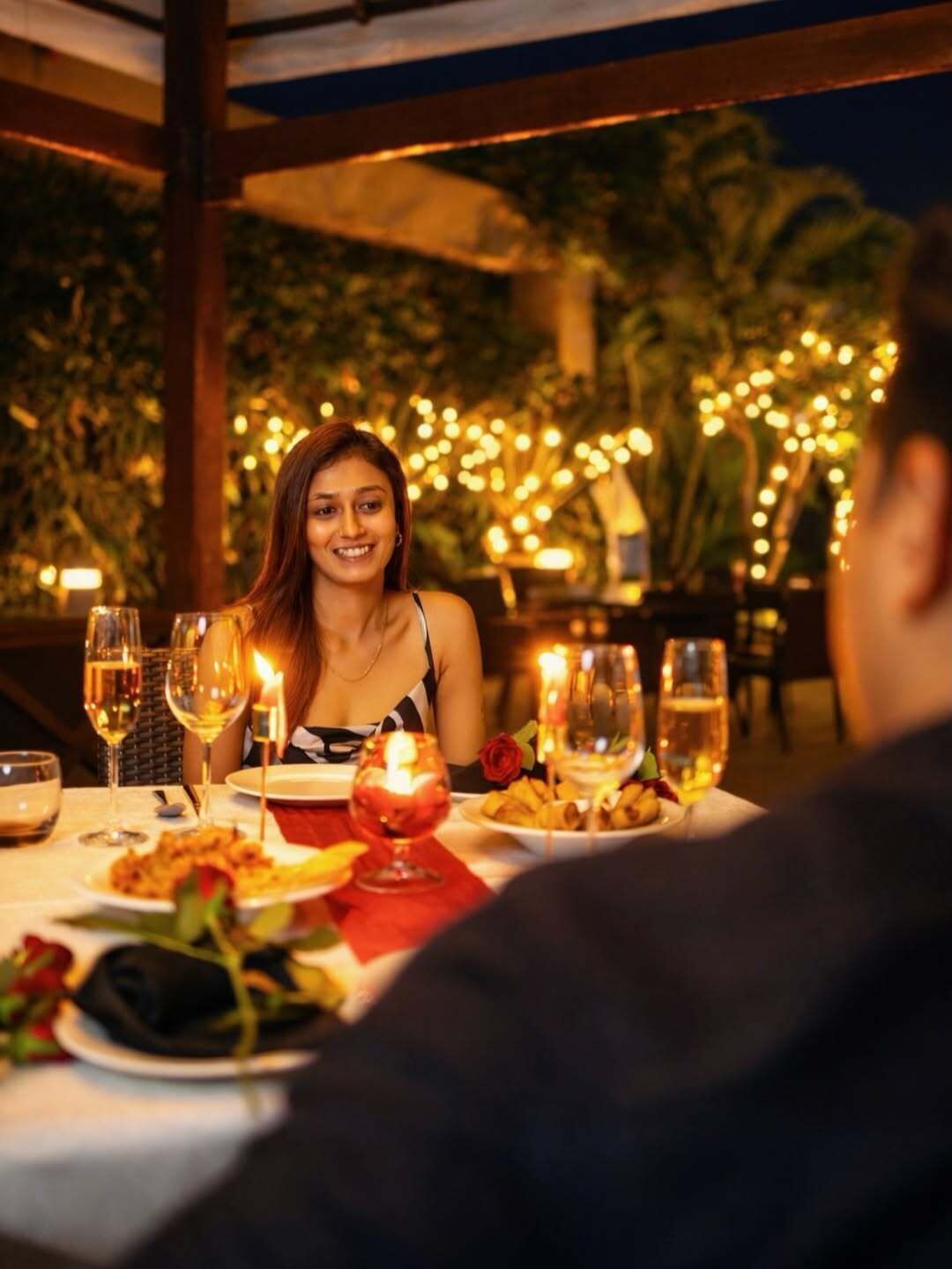 An outdoor dining area with tables, candles, and a warm ambiance.