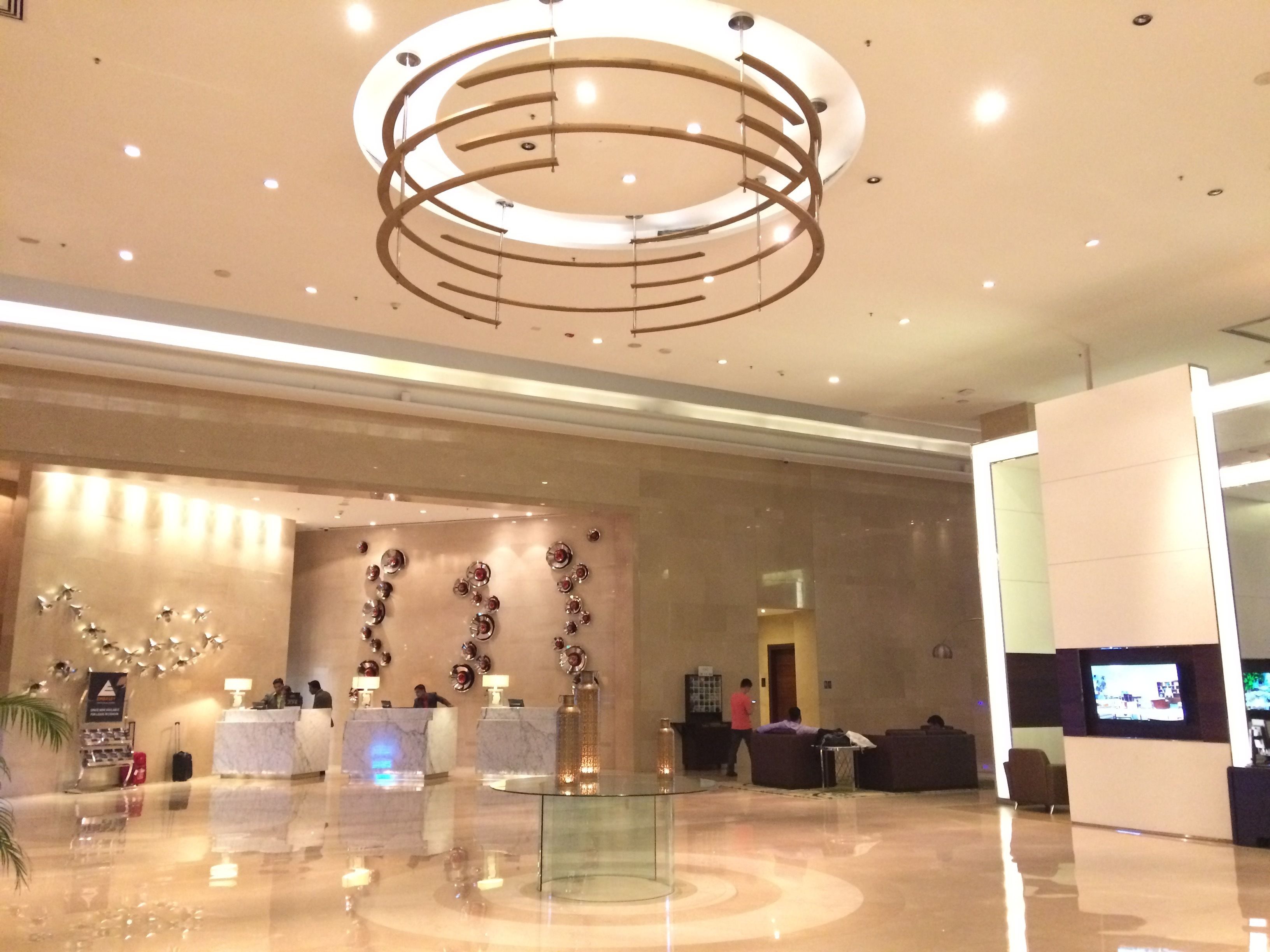 Eine moderne Lobby mit einer runden Deckenleuchte, Empfangstresen und einem Glastisch.