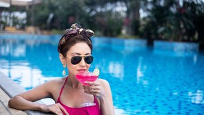A person in a pink swimsuit sitting by a pool with a drink. - Courtyard by Marriott Pune Chakan (Rajgurunagar)
