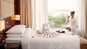 A hotel room with a bed, a nightstand, a lamp, and a view of greenery through the window. - Courtyard by Marriott Pune Chakan (Rajgurunagar)