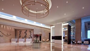 A spacious lobby with a modern chandelier, a reception desk, and a seating area. - Courtyard by Marriott Pune Chakan (Rajgurunagar)
