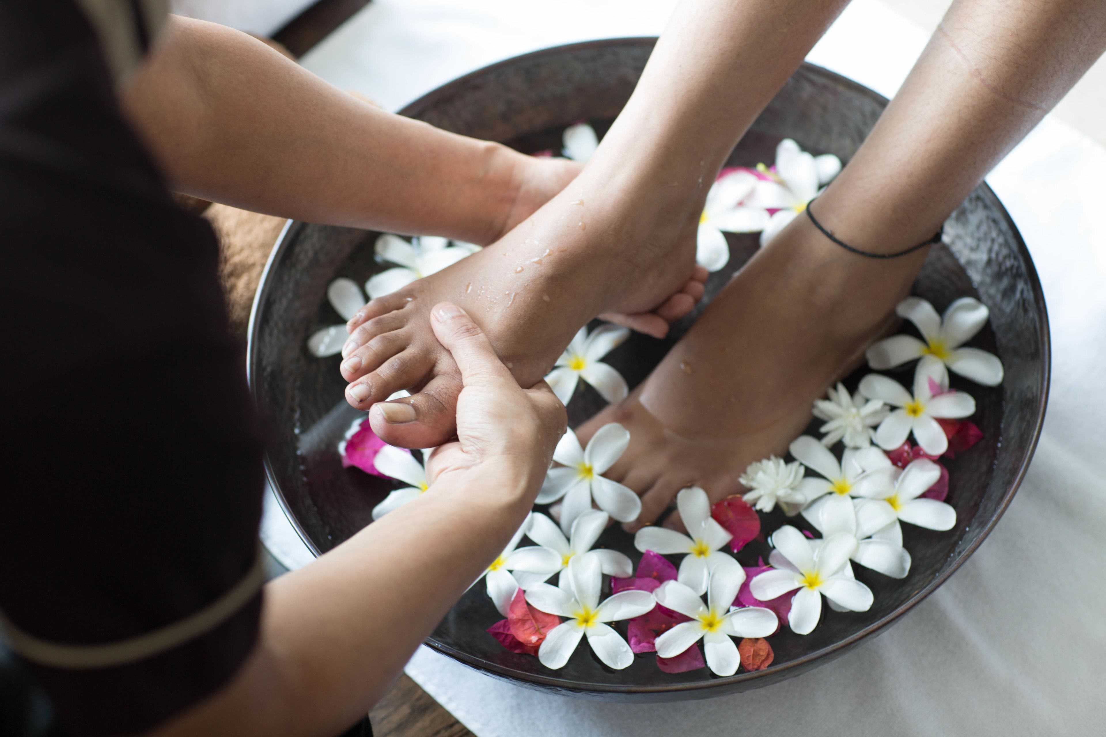 A bowl with feet submerged in water, surrounded by white flowers.