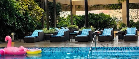 A swimming pool with lounge chairs and palm trees.