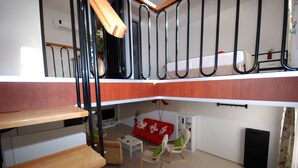 A multi-level living space with a wooden staircase, a red sofa, and a small dining area. - Vela Apart Hotel (Cesme)