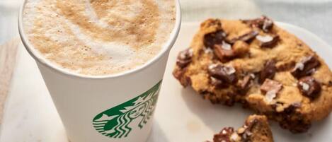 Una taza de Starbucks con una bebida espumosa y una galleta con chispas de chocolate.