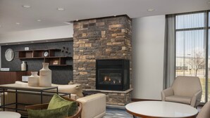 A modern living room with a stone fireplace, comfortable seating, and a large window offering a city view.