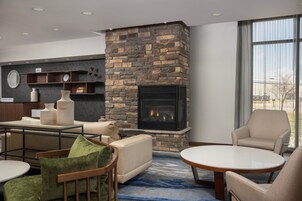 Una sala de estar moderna con chimenea de piedra, asientos cómodos y un amplio ventanal con vistas a la ciudad.