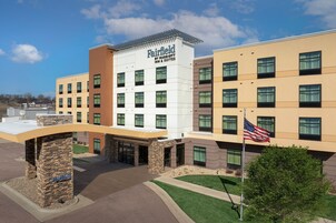 A Fairfield by Marriott Inn & Suites building with a stone entrance, multiple floors, and a flag.