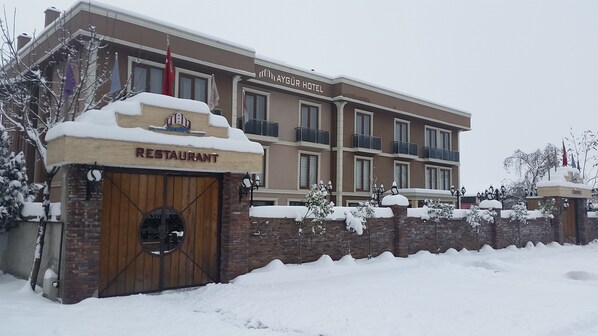 A hotel with a restaurant entrance, a brick wall, and snow-covered surroundings.