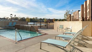 A poolside area with lounge chairs, a pool, and a view of buildings and trees. - SpringHill Suites Jackson North/Ridgeland (Ridgeland)