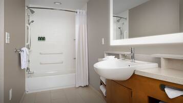 A modern bathroom with a bathtub, shower, and sink.