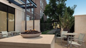 An outdoor patio area with a fire feature, seating, and a view of a building in the background. - SpringHill Suites Jackson North/Ridgeland (Ridgeland)