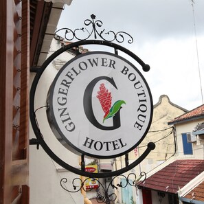 A circular sign with the text "GINGERFLOWER BOUTIQUE HOTEL" and a logo featuring a red flower and green leaves. - Gingerflower Boutique Hotel (Malacca City)