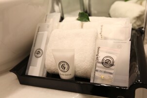Un baño con una bandeja negra que contiene artículos de tocador, incluyendo una toalla blanca, un tubo de loción corporal y un kit de afeitado.