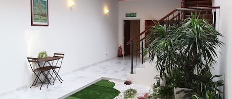 Un patio con zona de comedor, escalera y plantas en macetas.
