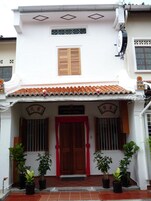 Un edificio con puerta roja, plantas en macetas y un letrero que dice 'Gingerflower Boutique Hotel'.