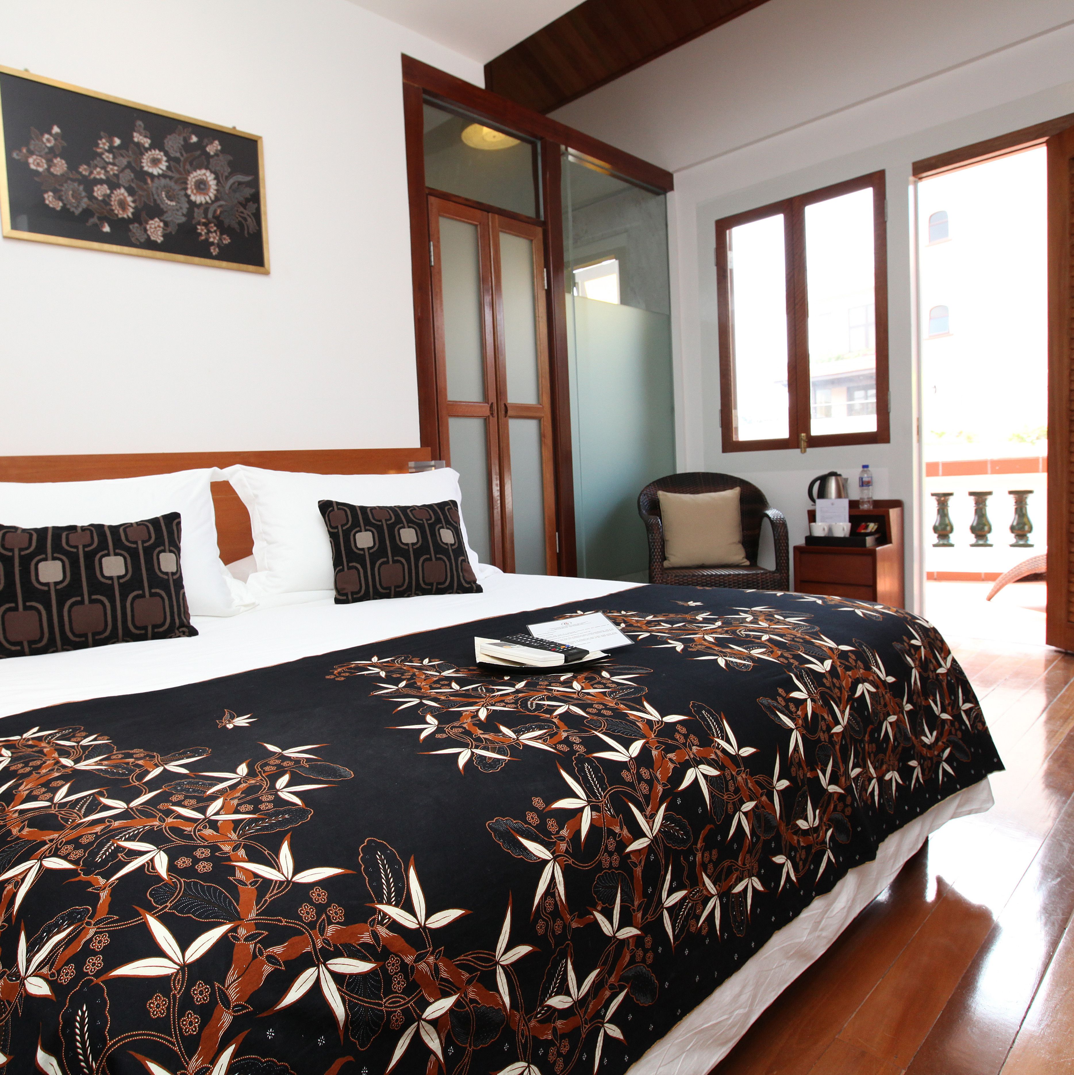 A hotel room with a large bed, a chair, a desk with a lamp, and a view of the outside.