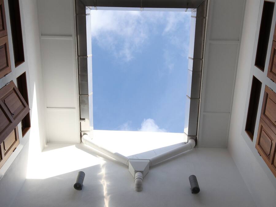 Um quarto com uma janela grande, paredes brancas e painéis de madeira nas laterais.