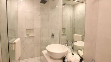 A modern bathroom with a glass-enclosed shower, a large white sink, and a mirror.