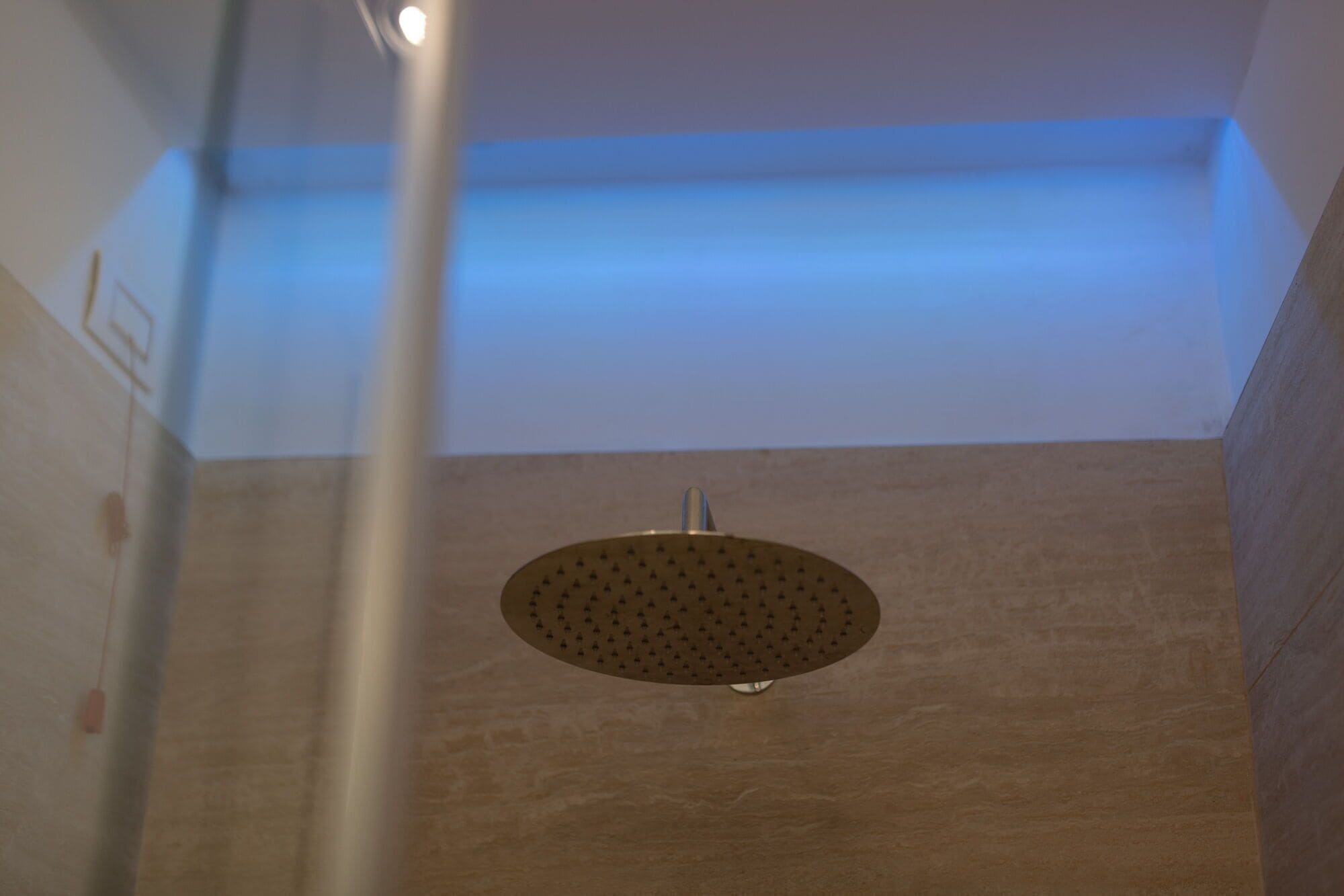 A shower with a circular drain and a blue light above it.