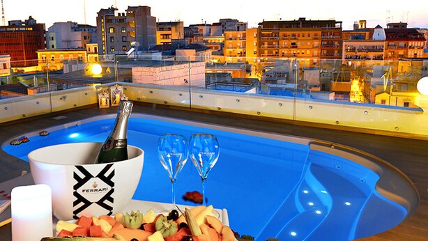 Un espace piscine aménagé sur le toit, avec une bouteille de champagne, des verres et des fruits.