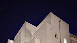 Un bâtiment moderne doté d’un toit plat et de grandes fenêtres, et comprenant une cour pavée de pierres.
